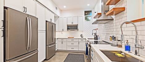 A modern kitchen with white cabinets, stainless steel appliances, and a built-in oven.