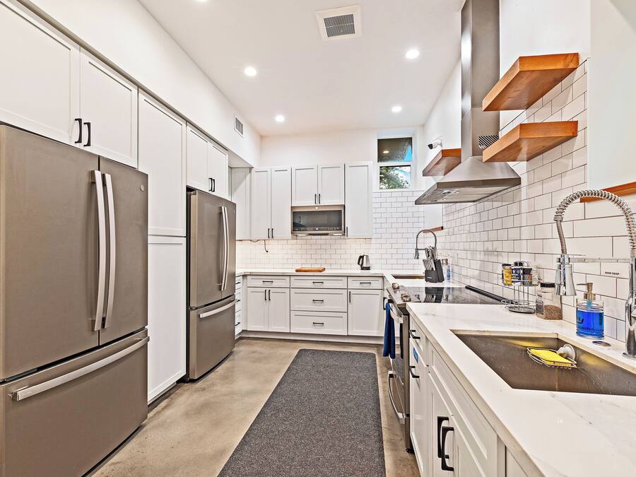 A modern kitchen with white cabinets, stainless steel appliances, and a built-in oven.