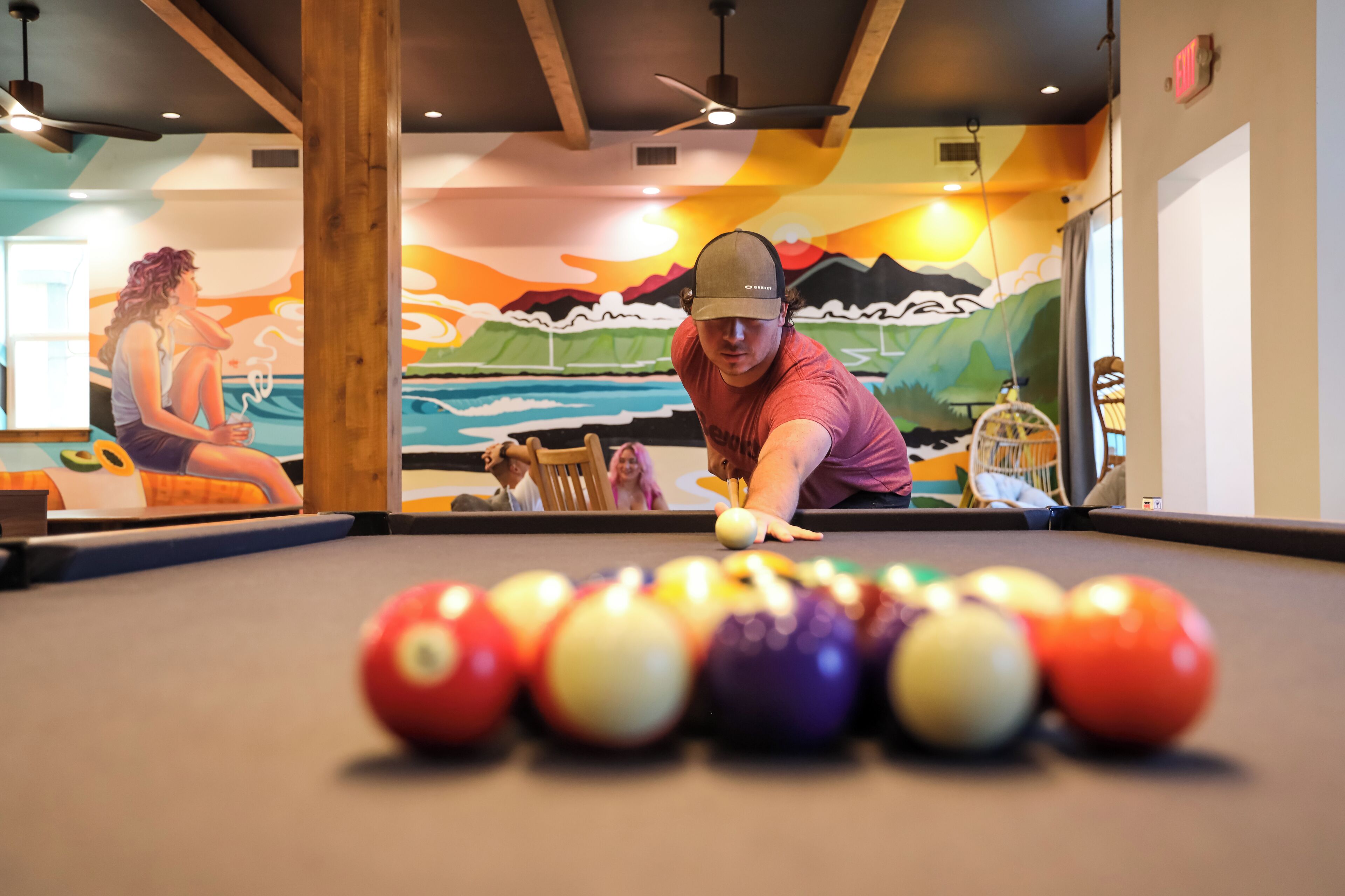 Une table de billard avec une fresque colorée en arrière-plan.
