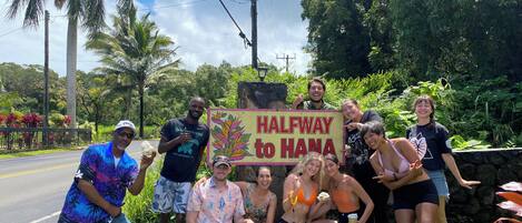 A group of people posing with a sign that reads "HALFWAY to HANA".