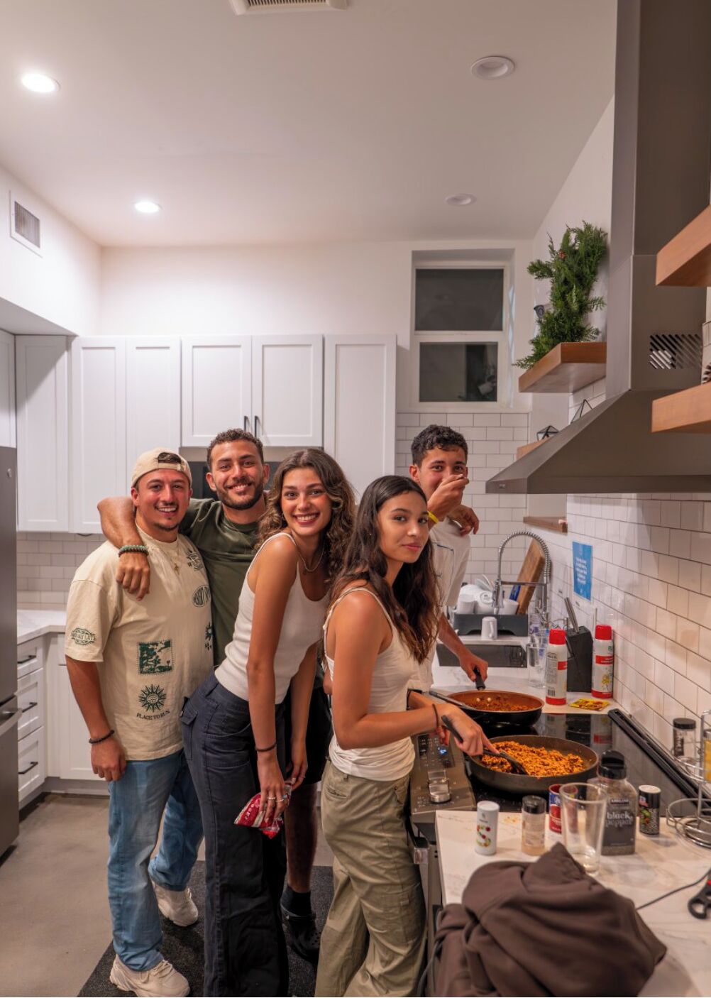 A modern kitchen with white cabinets, a central island, and a hanging plant.
