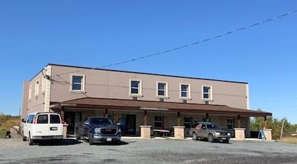 A two-story building with a flat roof and a single entrance. There are three cars parked in front.