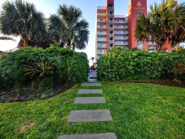 A pathway leading to a hotel with a red facade and balconies.