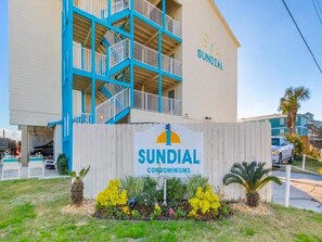 Ein Gebäude mit einem Schild, auf dem „SUNDIAL CONDOMINIUMS“ steht, und einer blauen und beigen Fassade.
