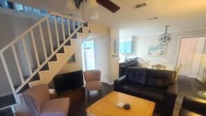 A living room with a staircase, a sofa, a coffee table, and a dining area. - Beautiful 3 Bedroom BEACHFRONT Condo - Sundial #F3 - Sleeps 10 (Gulf Shores)