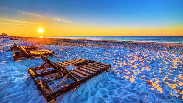 A beach with wooden lounge chairs and a sunset in the background. - Beautiful 3 Bedroom BEACHFRONT Condo - Sundial #F3 - Sleeps 10 (Gulf Shores)