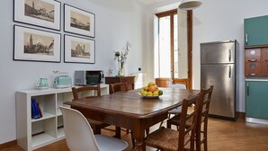 Ein Essbereich mit einem Holztisch, Stühlen, einer Obstschüssel und einem Kühlschrank.