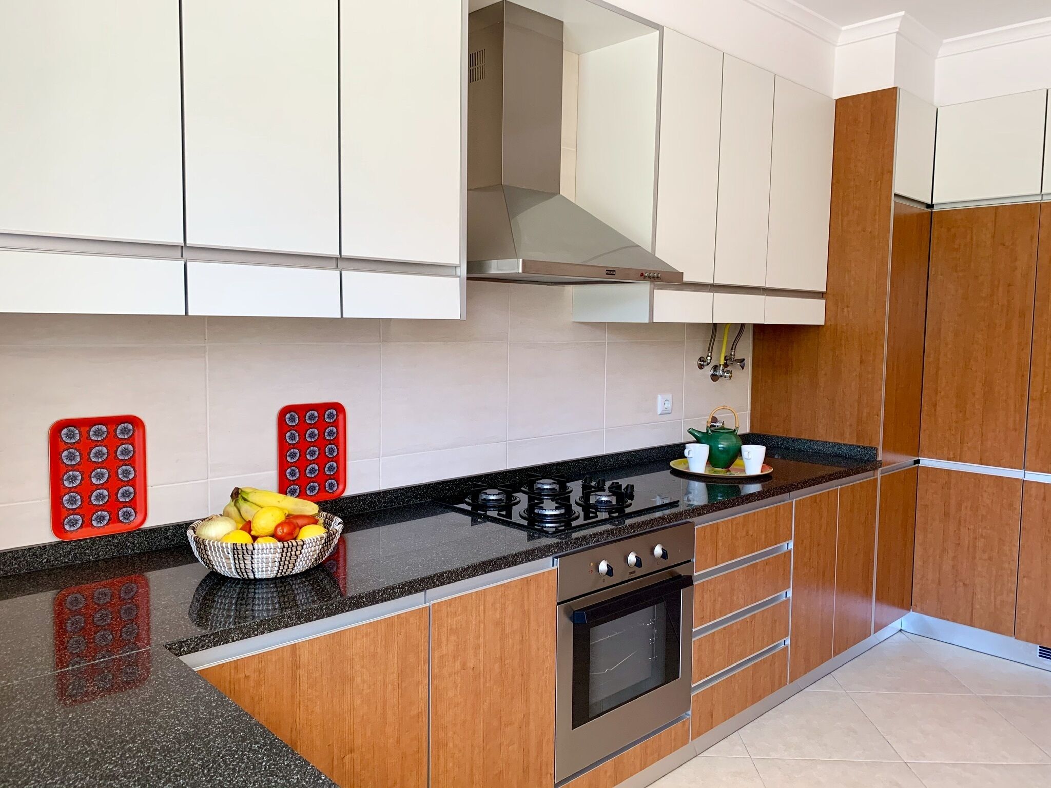 Een moderne keuken met houten kastjes, een zwart aanrecht en een gasfornuis.