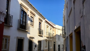 Uma rua estreita de paralelepípedos ladeada por edifícios com varandas e arquitetura tradicional.