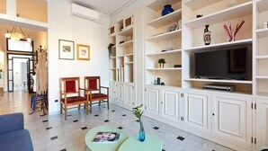 Un salon moderne comprenant un téléviseur, deux fauteuils, un canapé et une table basse.