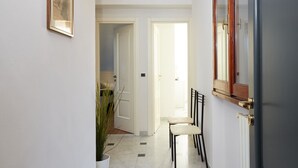 Un couloir avec une porte blanche, une plante en pot et une chaise.