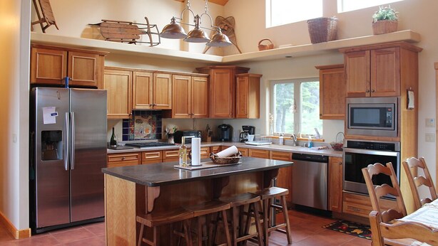 Una cocina amplia con armarios de madera, electrodomésticos de acero inoxidable y una isla central con taburetes de bar.