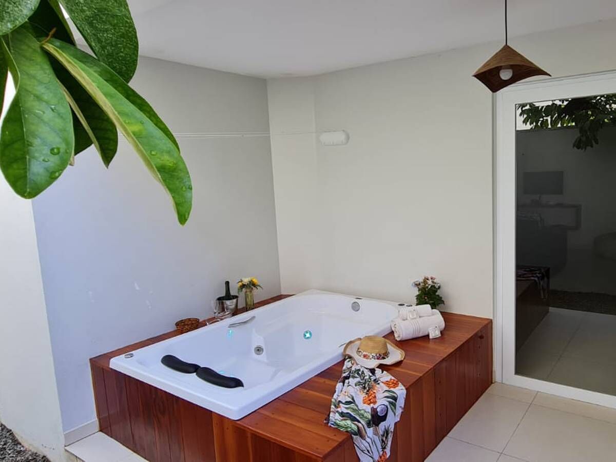 Un baño moderno con tocador de madera, una bañera grande y una mampara de ducha de vidrio.