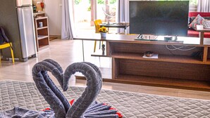 Une chambre avec un lit, une télévision, un coin cuisine et une fenêtre avec des rideaux.