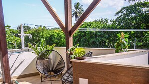 Un bain à remous surmonté d’une pergola en bois, entouré de chaises et de plantes en pot.