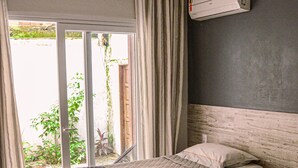 Une chambre d’hôtel avec deux lits, une porte-fenêtre coulissante donnant sur l’extérieur et un climatiseur fixé au mur.