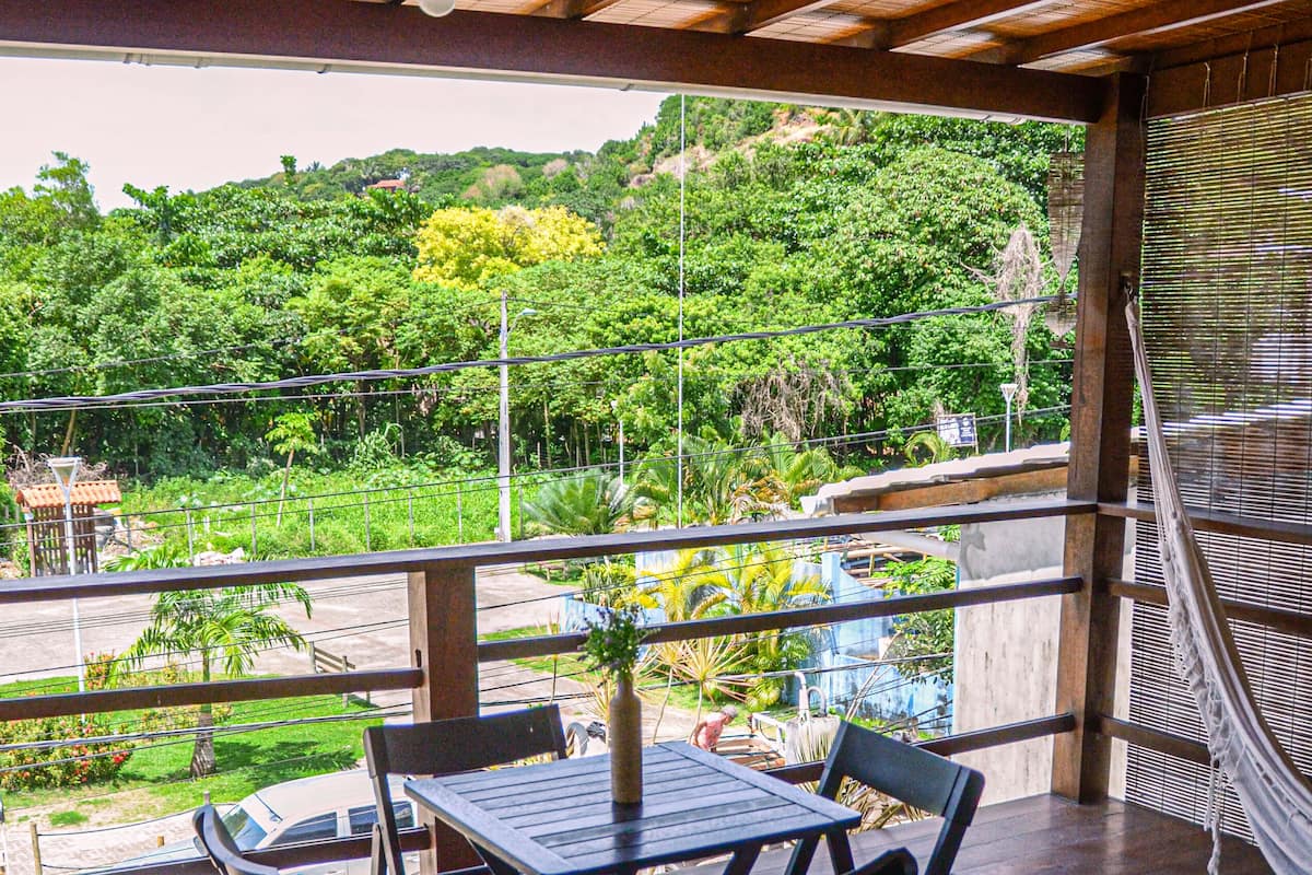 A wooden deck with a table and chairs, overlooking a lush green landscape.