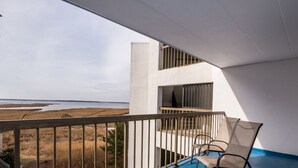 A balcony with a view of the beach, a chair, and a railing. - Bay Princess renovated and decorator furnished, bayfront condo in convenient midtown location (OCEAN CITY)
