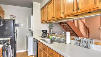 A kitchen with wooden cabinets, a refrigerator, a dishwasher, and a coffee maker.
