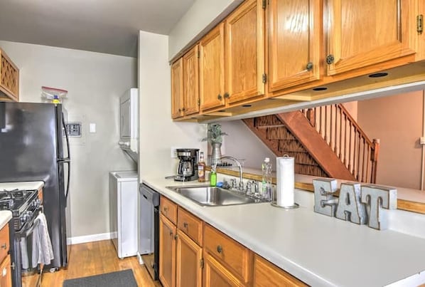 A kitchen with wooden cabinets, a refrigerator, a dishwasher, and a coffee maker.