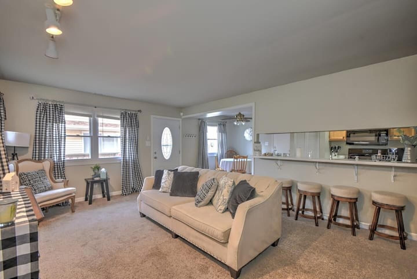 A living room with a beige sofa, a coffee table, and a dining area with a kitchen in the background.