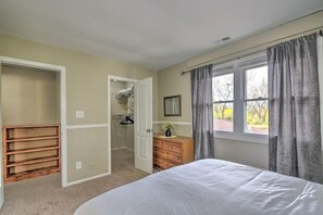 Une chambre à coucher comprenant un lit, un dressing, une commode et une fenêtre avec des rideaux.