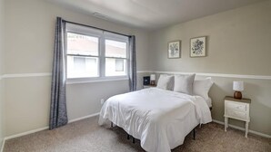 Un dormitorio con una cama, una mesita de noche, una lámpara y dos cuadros colgados en la pared.