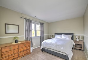 A bedroom with a bed, dresser, nightstands, and a window with curtains.