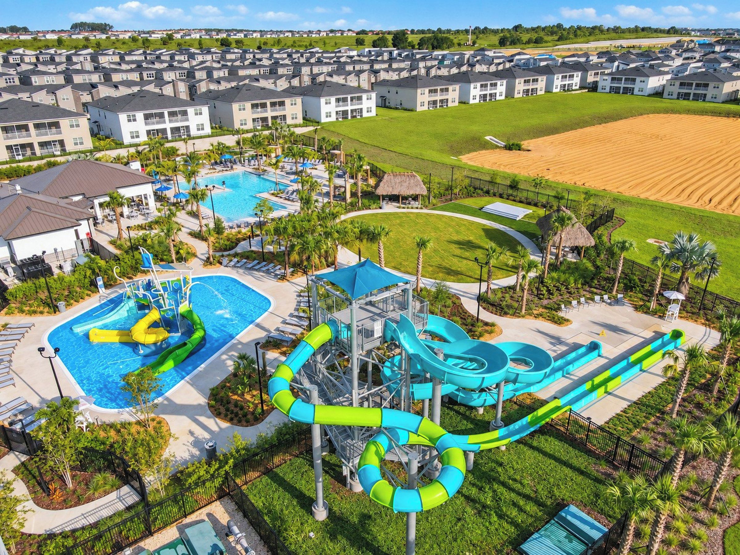 A residential area with a large swimming pool, water slides, and a well-maintained lawn.