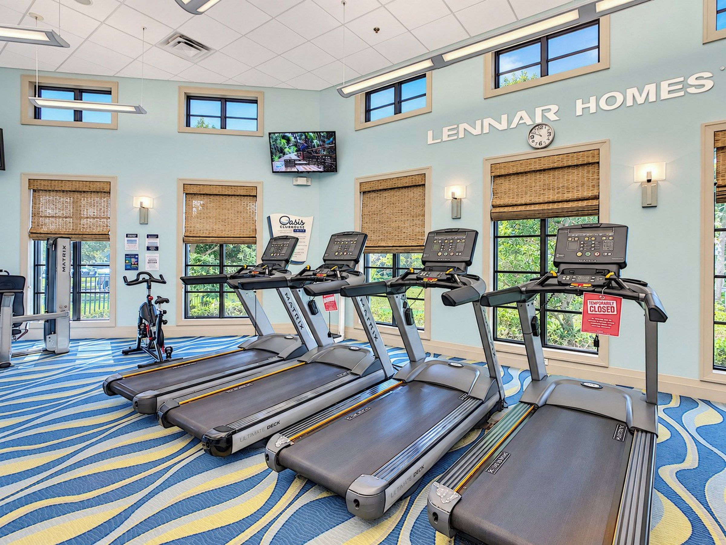 Un gimnasio con cintas de correr, bicicletas estáticas y una pantalla de televisión.