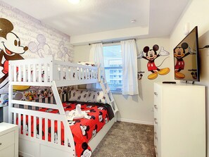 Habitación infantil con literas, decoración de Mickey Mouse y un televisor.