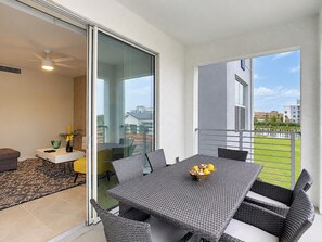 A balcony with a table and chairs, a small sofa, and a window with a view of buildings and greenery.