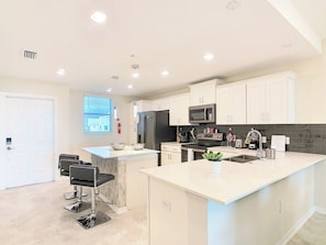 A modern kitchen with white cabinetry, stainless steel appliances, and a central island.