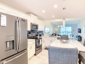 A modern kitchen with stainless steel appliances, a central island, and a dining area with a view.