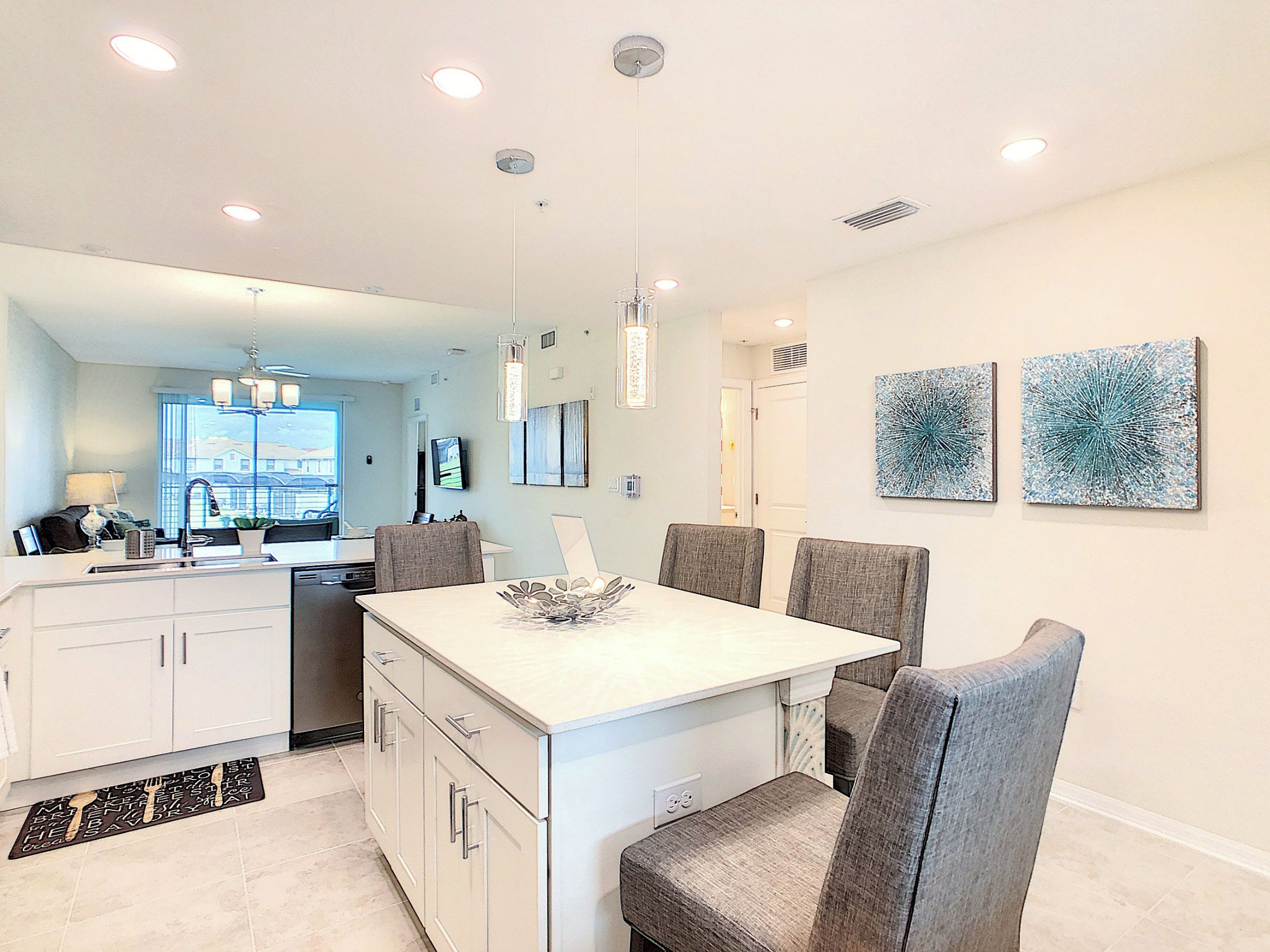 A modern kitchen with a dining area, white cabinetry, and a central island.