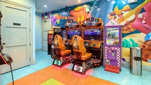 Una habitación con juegos de arcade, una puerta con el letrero "Solo personal" y un mural en la pared.