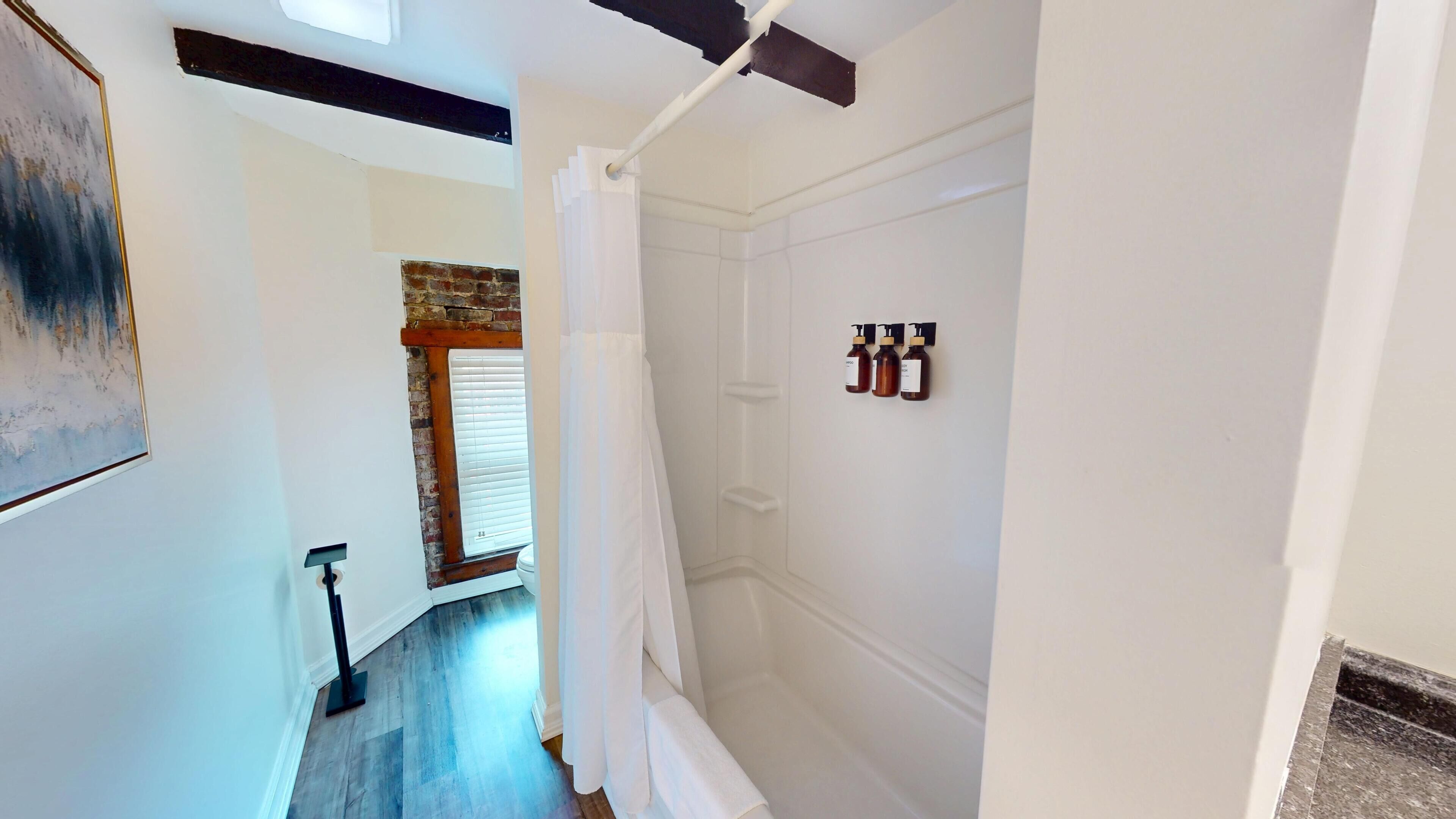 Une salle de bain moderne équipée d’une douche, de toilettes et d’une fenêtre avec stores.