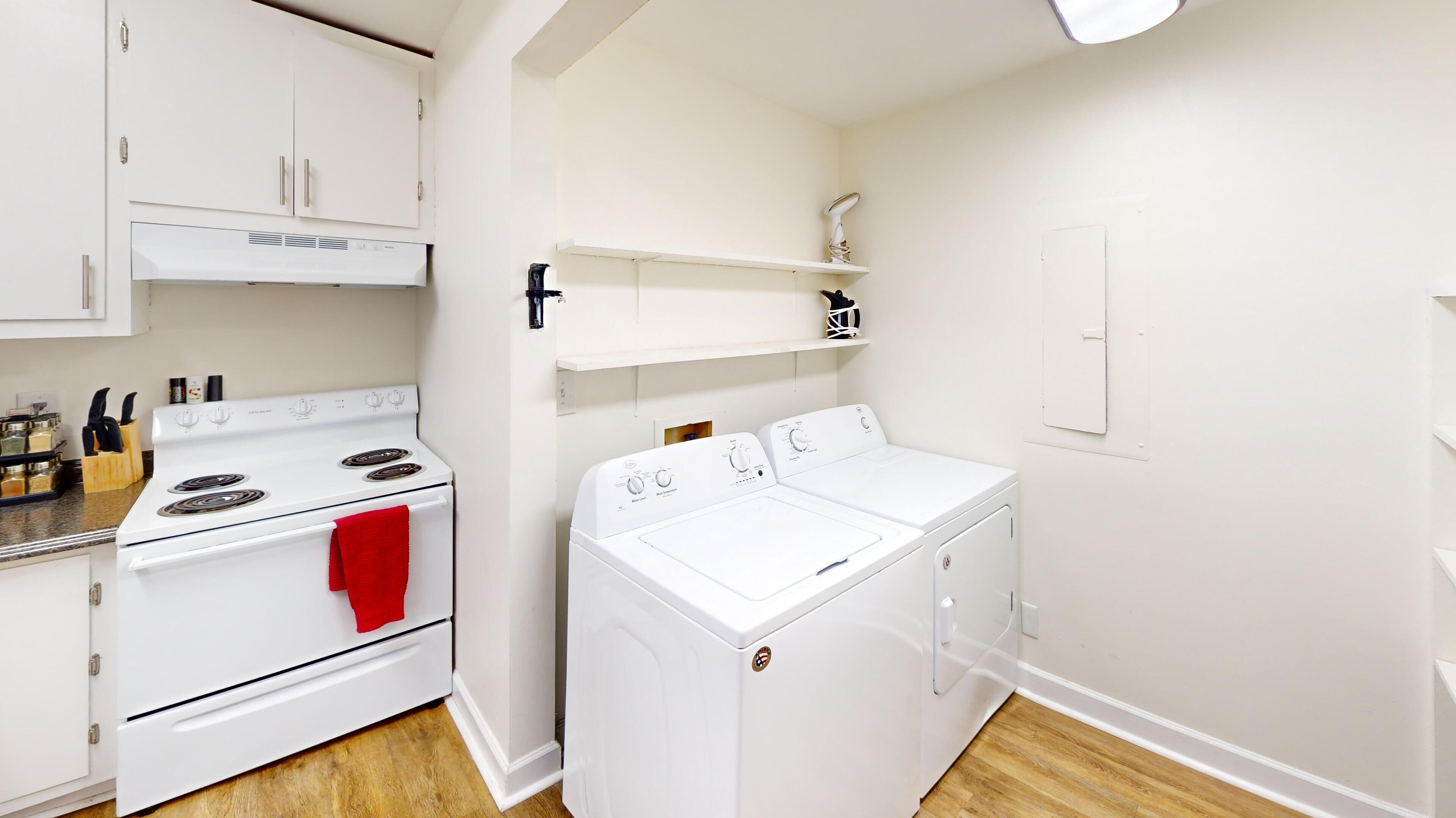 A compact kitchen with a stove, oven, and a front-loading washer.