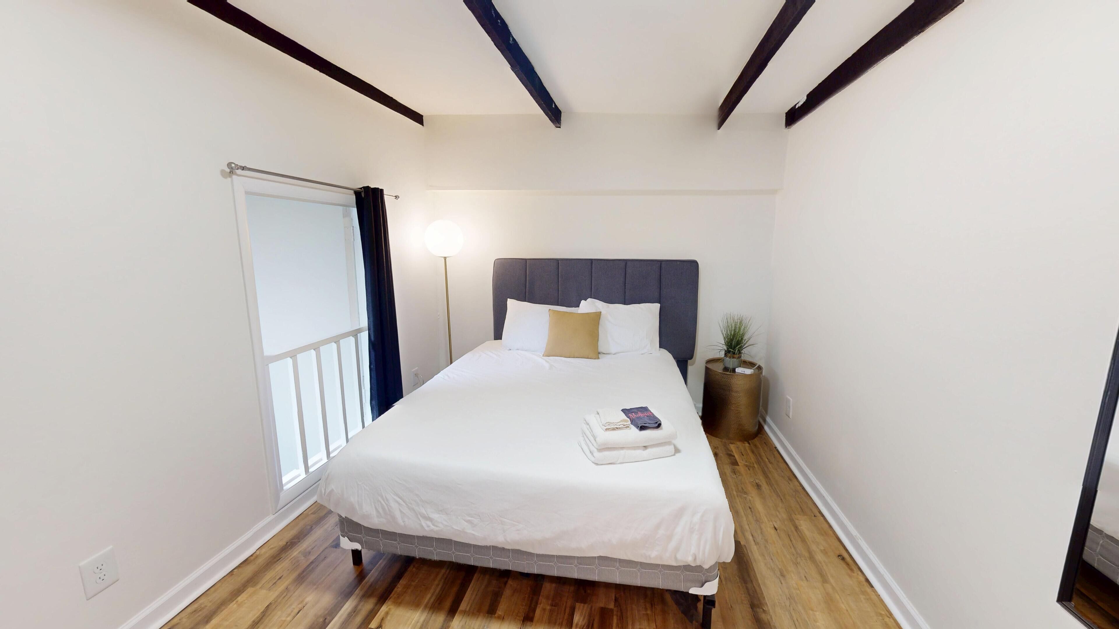 A bedroom with a bed, bedside lamp, and a small potted plant.