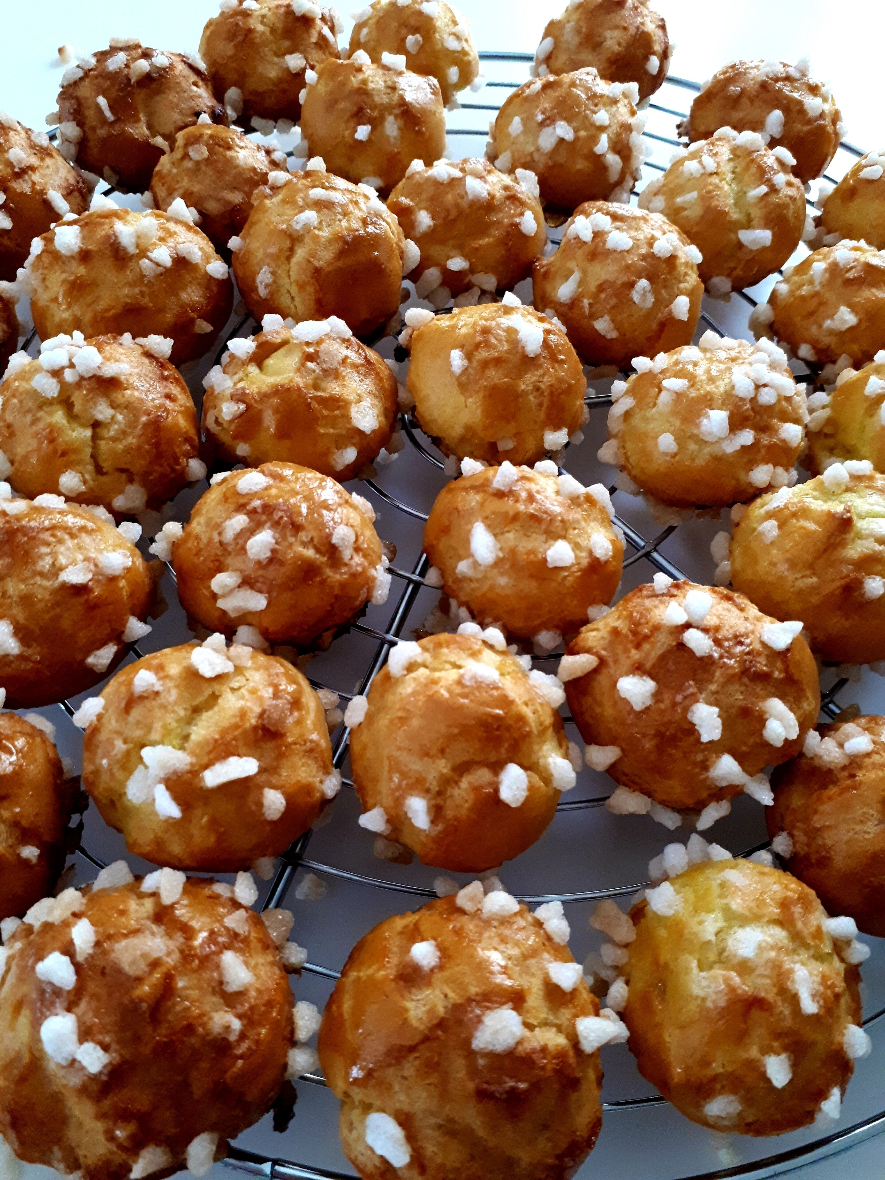 Una rejilla con bollos redondos cubiertos de azúcar.