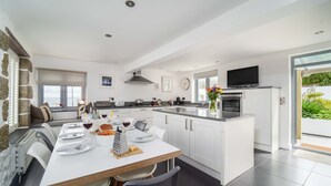 A modern kitchen with white cabinetry, a dining area with a white table, and a large window.