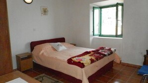 A bedroom with a bed, a nightstand, a window with green shutters, and a wall-mounted light. - Villa Soti - Two-Bedroom Apartment with Sea View (Mlini)