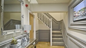 A hallway with a staircase, a mirror, a framed picture, and a small table with a plant. - 2 bedroom accommodation in Scarborough (Scarborough)