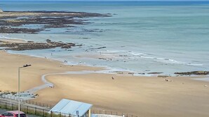 A beach with a clear view of the ocean, a sandy shore, and a few people walking. - 2 bedroom accommodation in Scarborough (Scarborough)