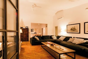 Uma sala de estar com um sofá, uma mesa de centro e uma área de jantar com mesa e cadeiras.