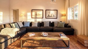 A living room with a dark-colored sofa, a wooden coffee table, and two framed pictures on the wall. - Cosy country house with heatable swimming pool and sea view. (Faro)