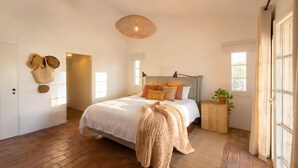 A bedroom with a bed, a bedside table, a hanging lamp, a door, and a window. - Cosy country house with heatable swimming pool and sea view. (Faro)