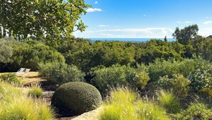 A landscaped garden with a stone pathway, a spherical hedge, and a view of the sea. - Cosy country house with heatable swimming pool and sea view. (Faro)