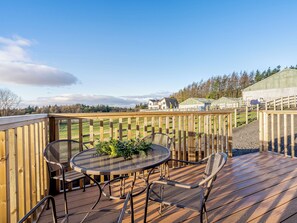 A wooden deck with a round table and chairs, surrounded by a wooden fence. - The Paddocks - UK7112 (Dollar)