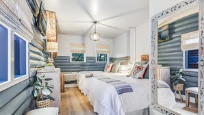 Un dormitorio con una cama grande, mesitas de noche, un espejo y un ventilador de techo.
